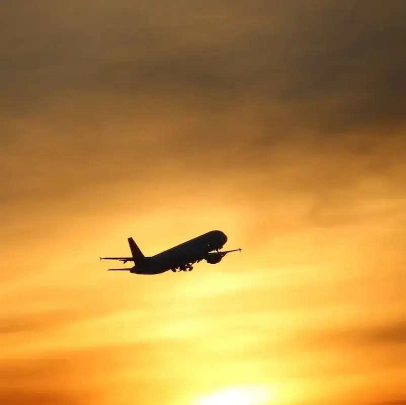 Ein Flugzeug fliegt in den Sonnenuntergang.